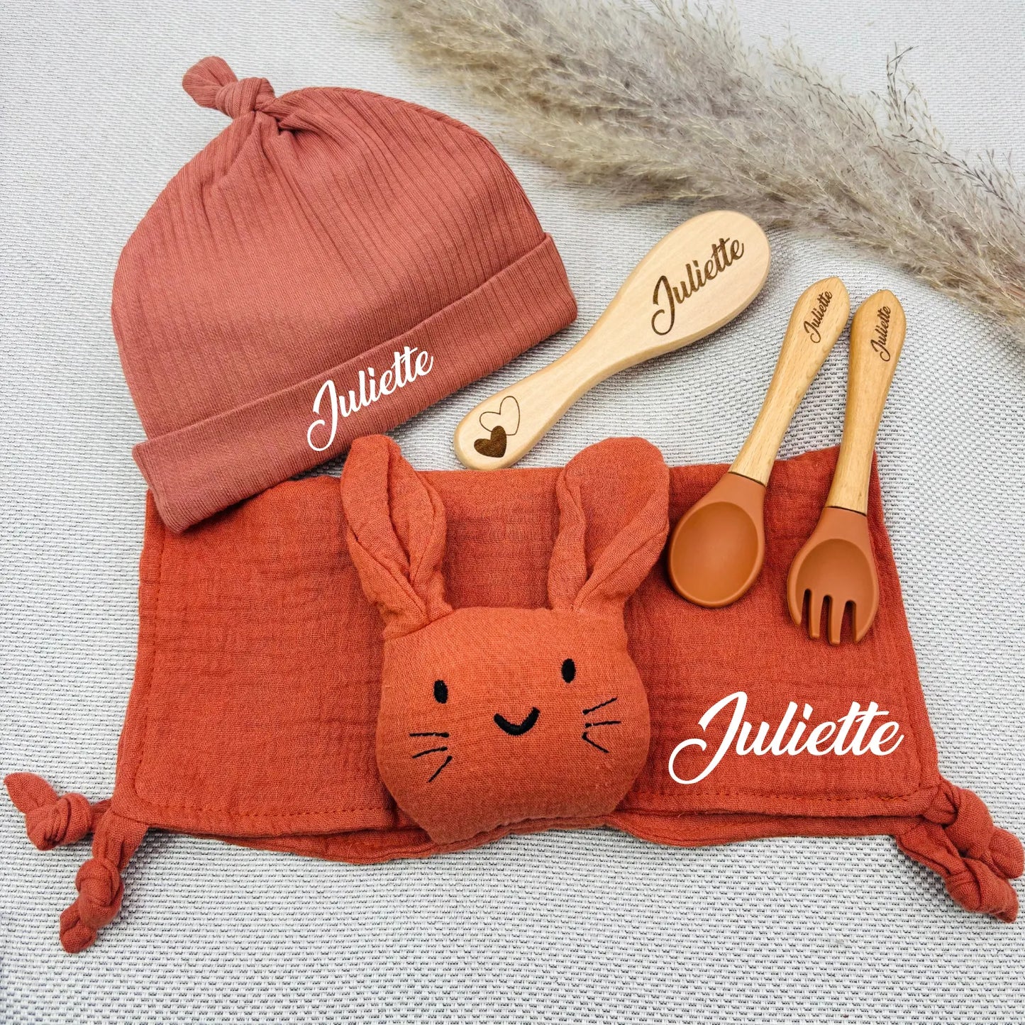 Coffret bébé Juliette avec doudou lapin rouge terracotta, bonnet assorti, couverts en silicone gravé et brosse en bois. Cadeau fille authentique.