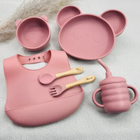 Kit repas bébé rose en silicone personnalisé avec prénom : assiette, bol, couverts, tasse anti-fuite et bavoir souple.