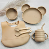 Vaisselle bébé personnalisée beige en silicone : assiette panda, bol, bavoir, tasse et couverts prénom gravé en bois.